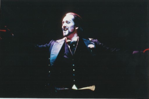 Christian Van Horn as Méphistophélès in Yale Opera’s 2001 Faust, arms spread on a dark stage