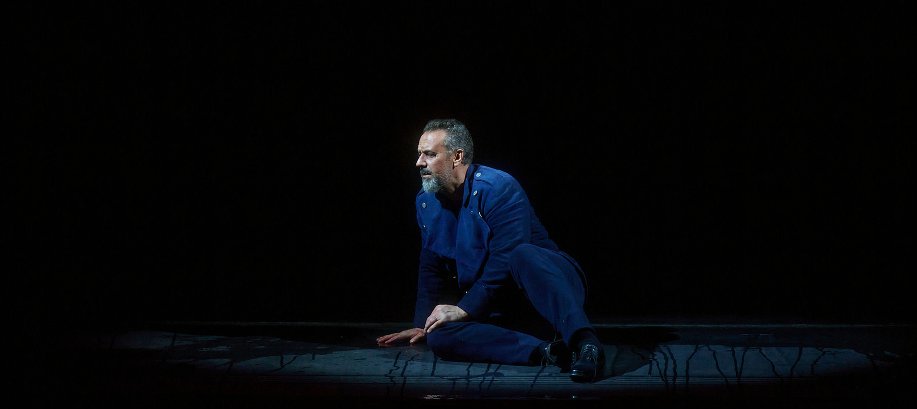 Christian Van Horn as Duke Bluebeard seated alone on a dark stage in the Canadian Opera Company’s Bluebeard’s Castle.