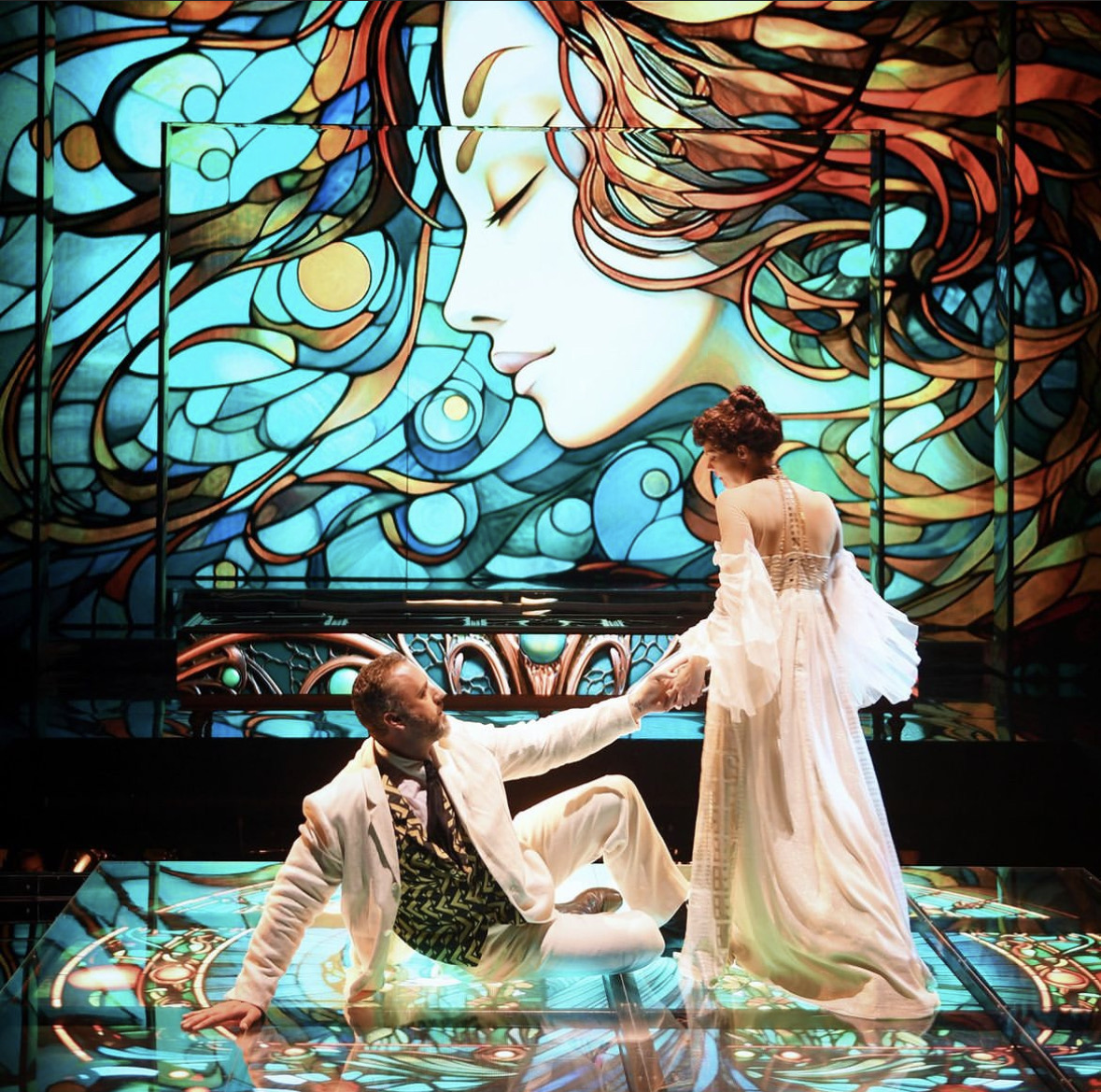 Christian Van Horn as Duke Bluebeard reaches toward Sara Gartland as Judith against a colorful projected backdrop in Bluebeard’s Castle.