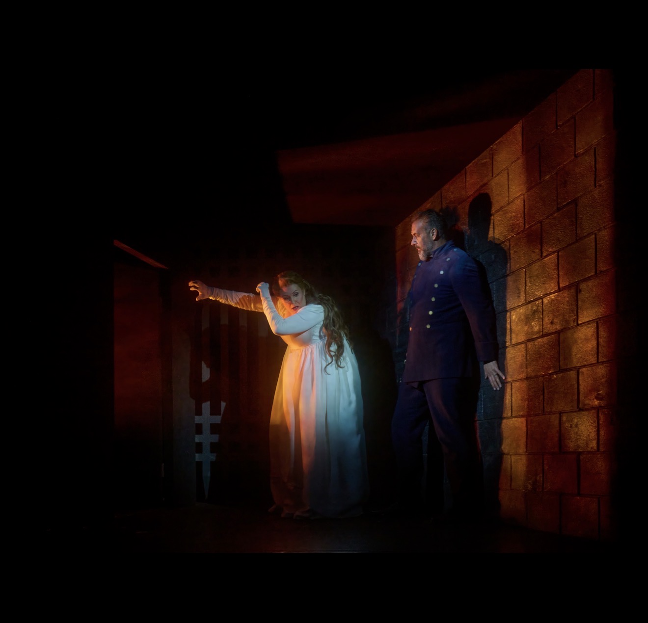 Karen Cargill as Judith gestures beside Christian Van Horn as Bluebeard in a red-lit castle scene.