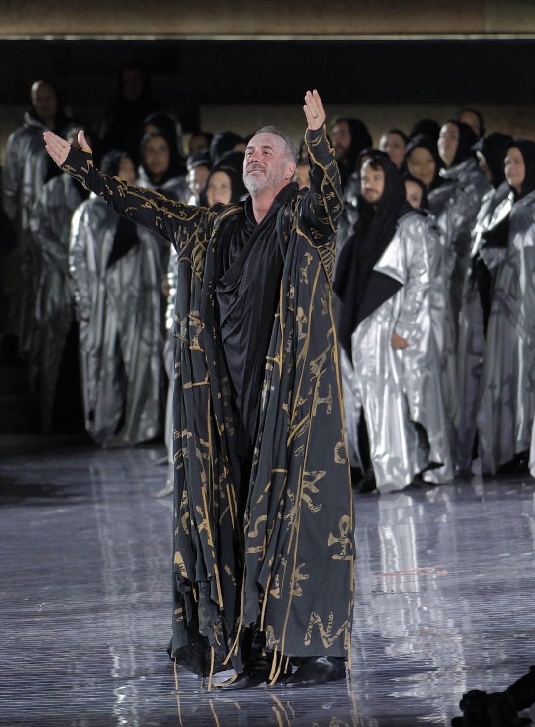 Christian Van Horn as Zaccaria onstage at the Arena di Verona in a black and gold robe, arms raised.